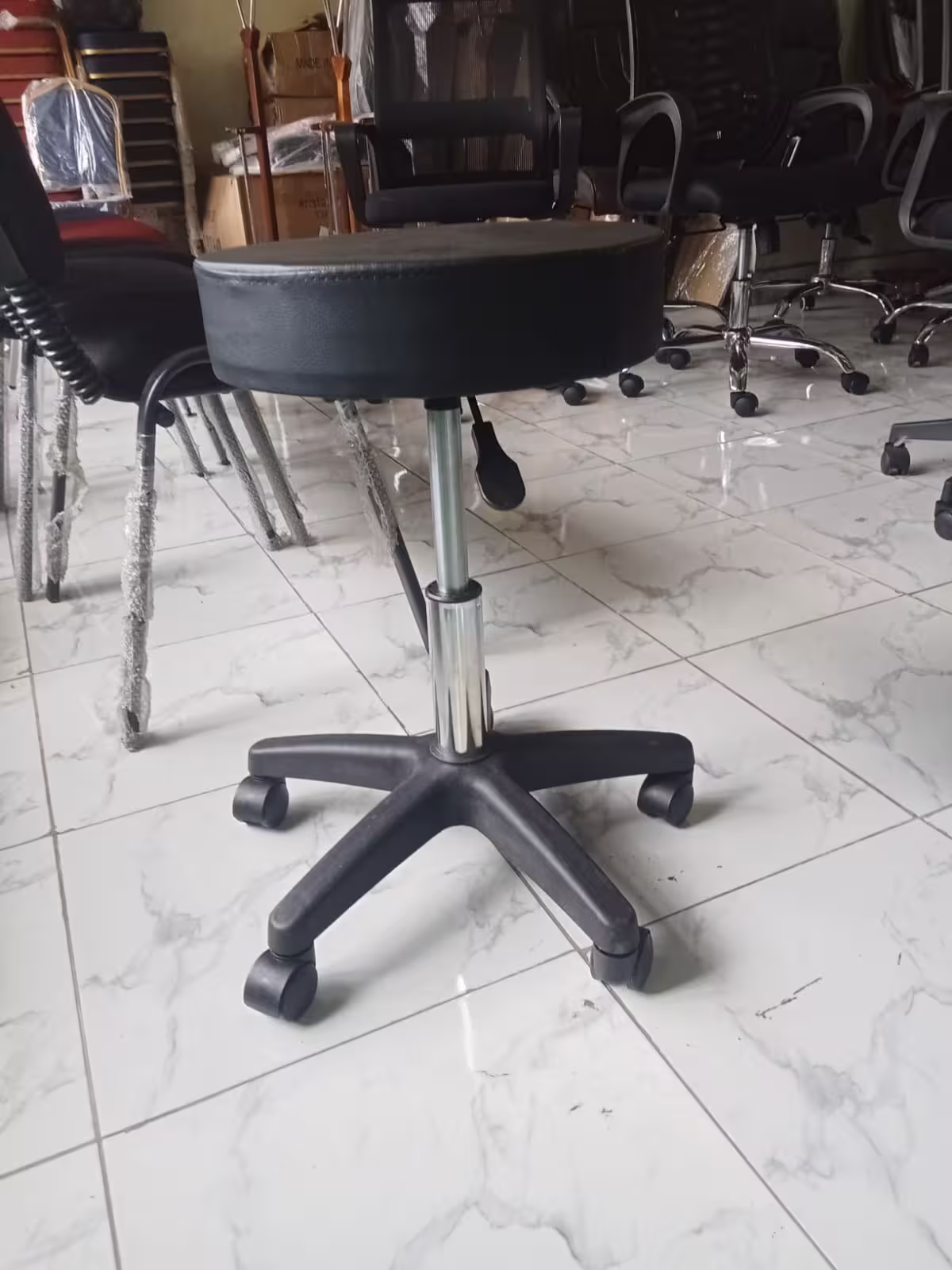 Swivel leather barstool with padded black seat, height adjustment lever, chrome gas lift, five-star base, and caster wheels.