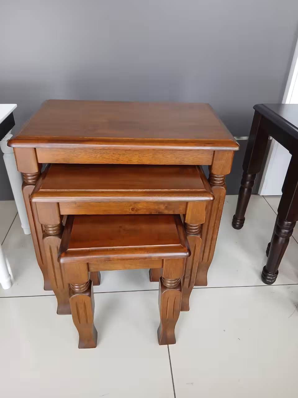 3 piece nest of stools with rich mahogany wood finish, carved wooden legs, and space-saving nesting design.